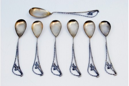 Conjunto de seis colheres de café e pá de açúcar em prata com cabos torcidos e aplicações de flores nos cabos.